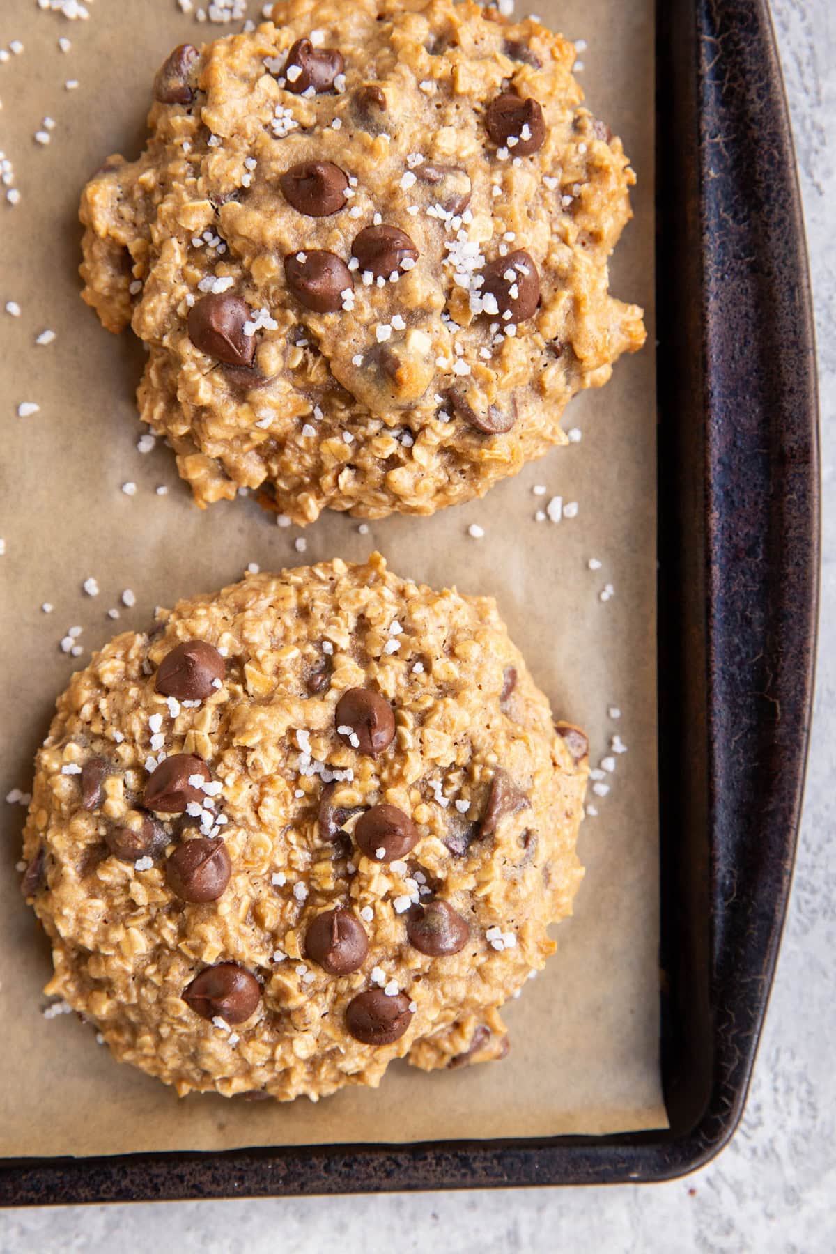 Tahini cookies sprinkled with coarse sea salt on a parchment-lined cookie sheet, fresh out of the oven and ready to eat.