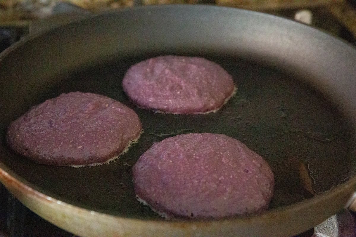Skillet with purple pancakes cooking.