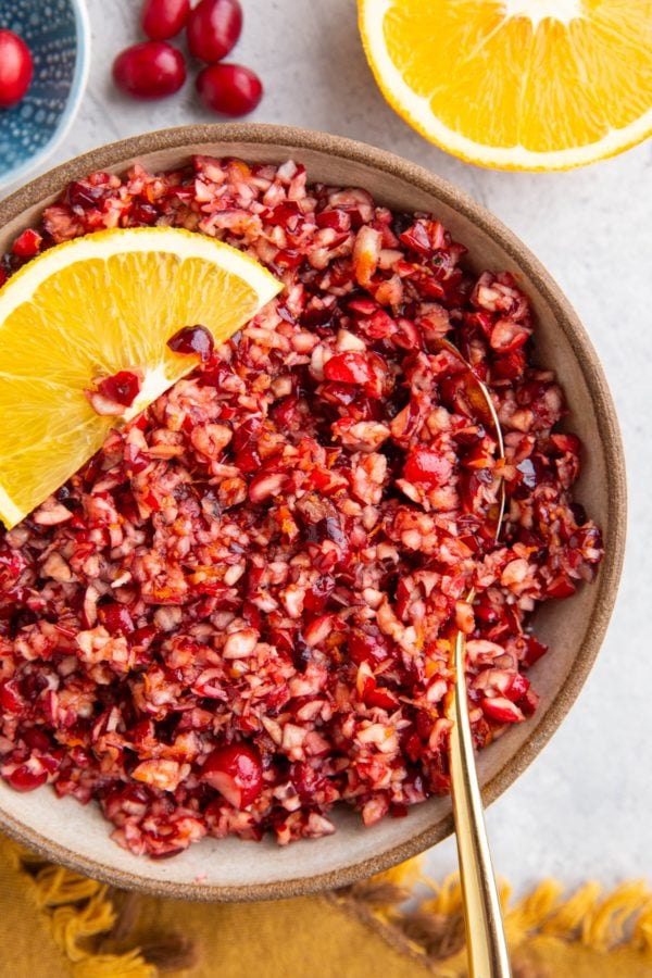 Cranberry relish in a ceramic bowl with fresh orange slice in the bowl.