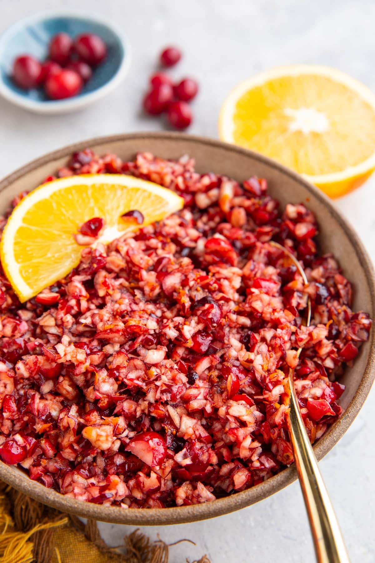 Cranberry relish in a bowl with fresh orange in the background.