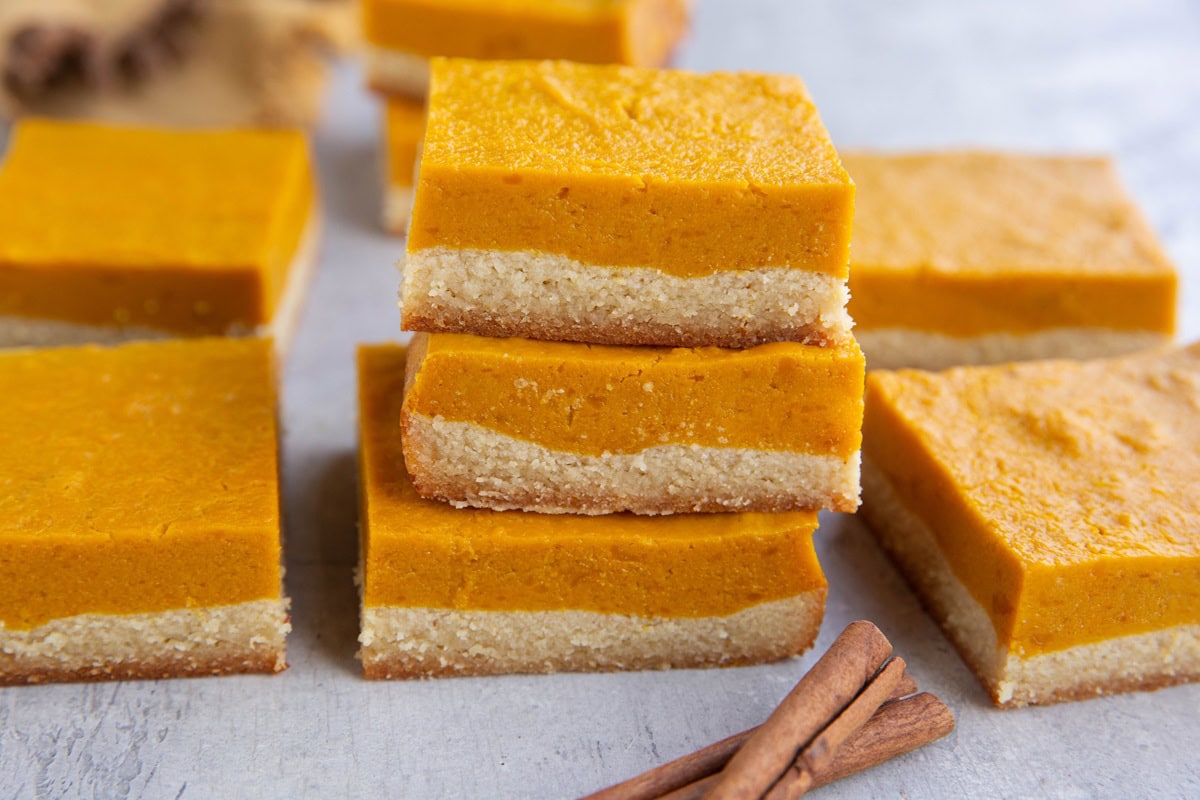 Stack of kabocha squash bars and more bars to the side with two cinnamon sticks.