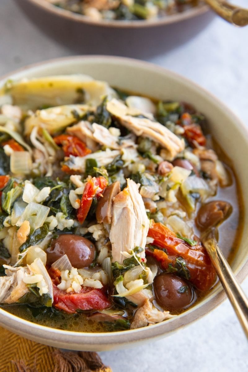 Mediterranean Chicken Soup in a bowl with a golden spoon.