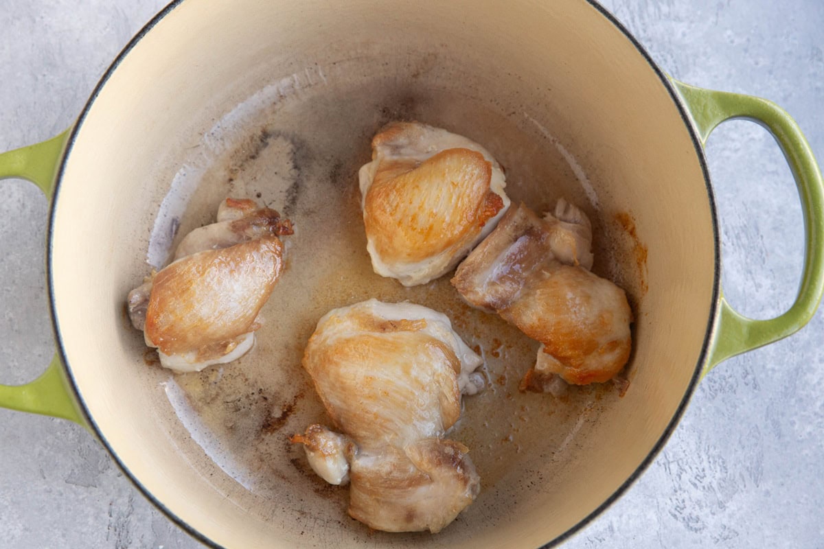 Large pot with browned chicken thighs
