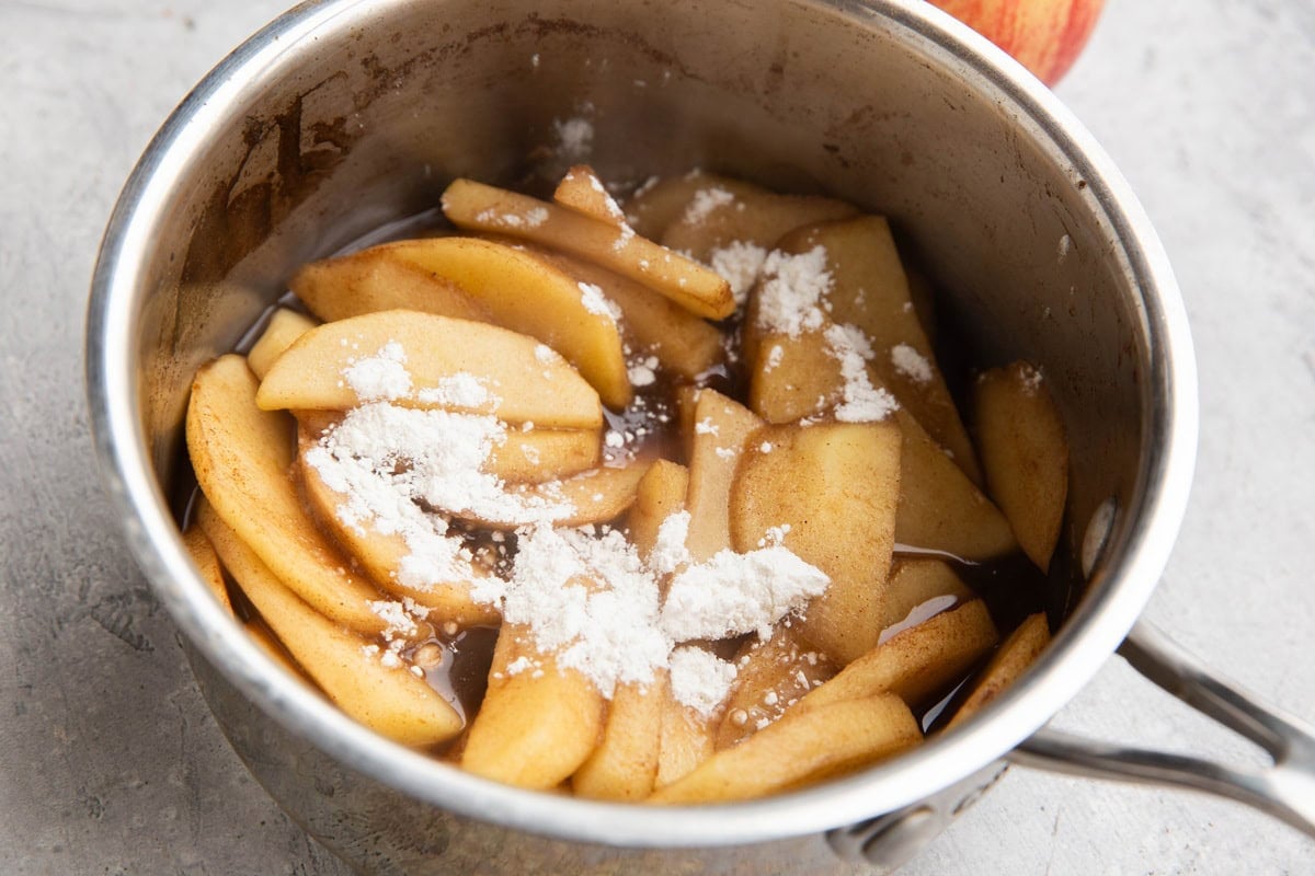 Saucepan full of stewed apples with flour sprinkled on top, to be mixed in to thicken the sauce.