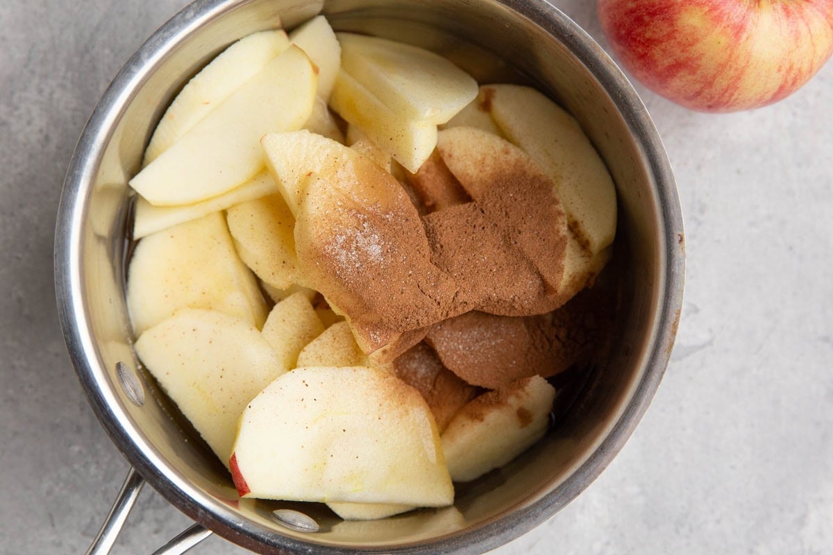 Saucepan full of sliced apples, cinnamon, pure maple syrup, apple cider, and salt.