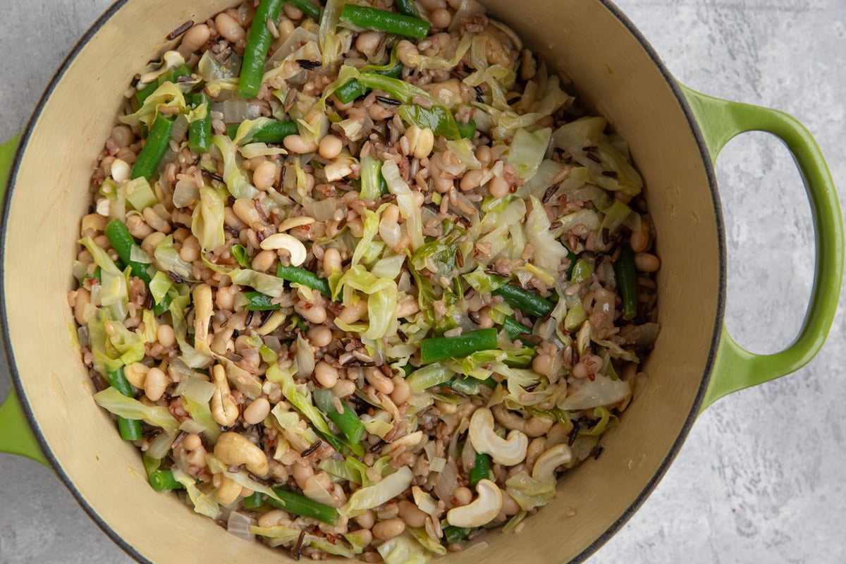 Large pot full of wild rice, white beans, green beans, cabbage, onion, garlic, and cashews. Ready to serve.