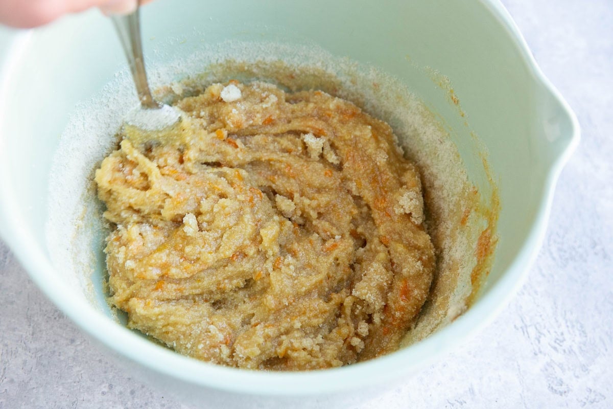 Stirring cookie dough in a mixing bowl for orange cookies.