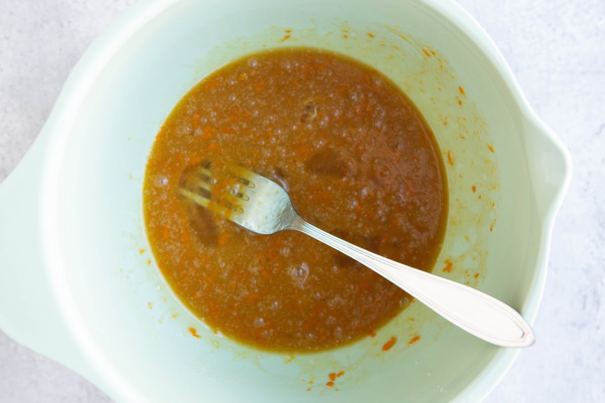 Wet ingredients for cranberry orange cookies in a mixing bowl.