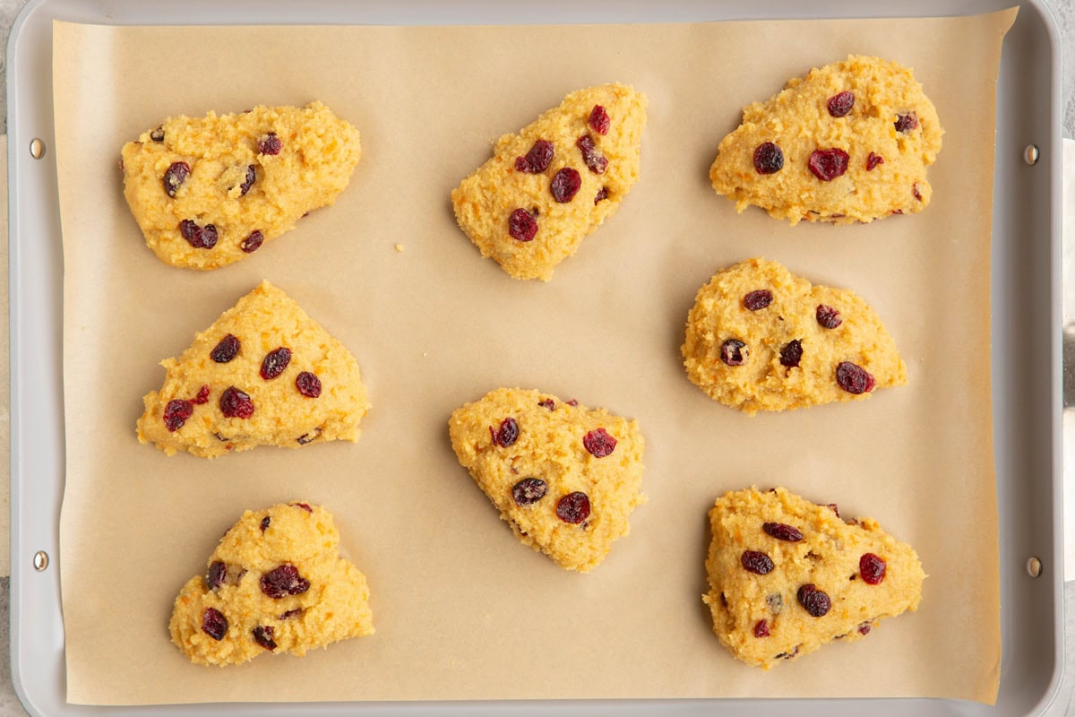Large baking sheet with cranberry orange scone dough on top of parchment paper, ready to go into the oven.