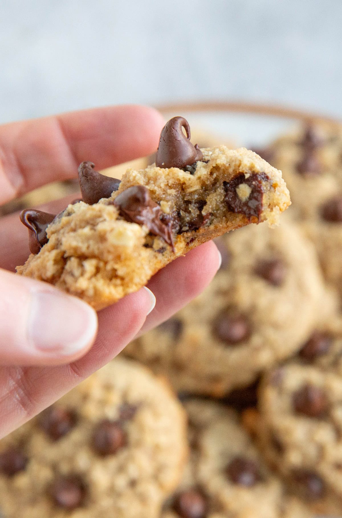 Hand holding a cookie with a bite taken out to see the gooey inside.