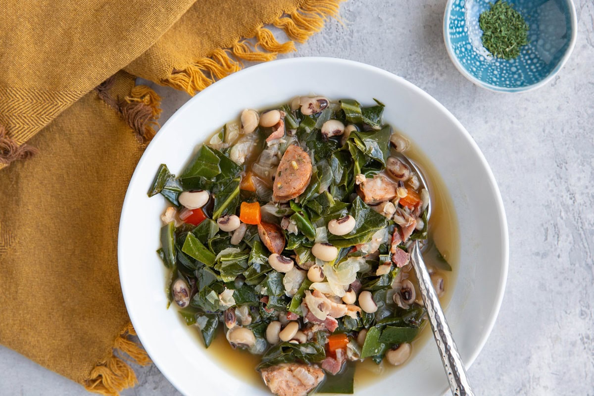 Bowl of black eyed pea soup with collard greens and sausage.