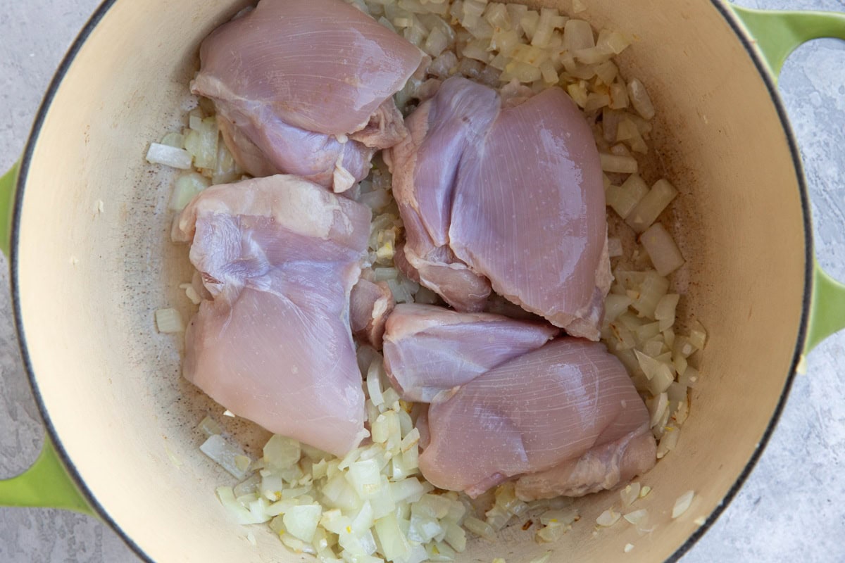 Large pot with onions and chicken inside.