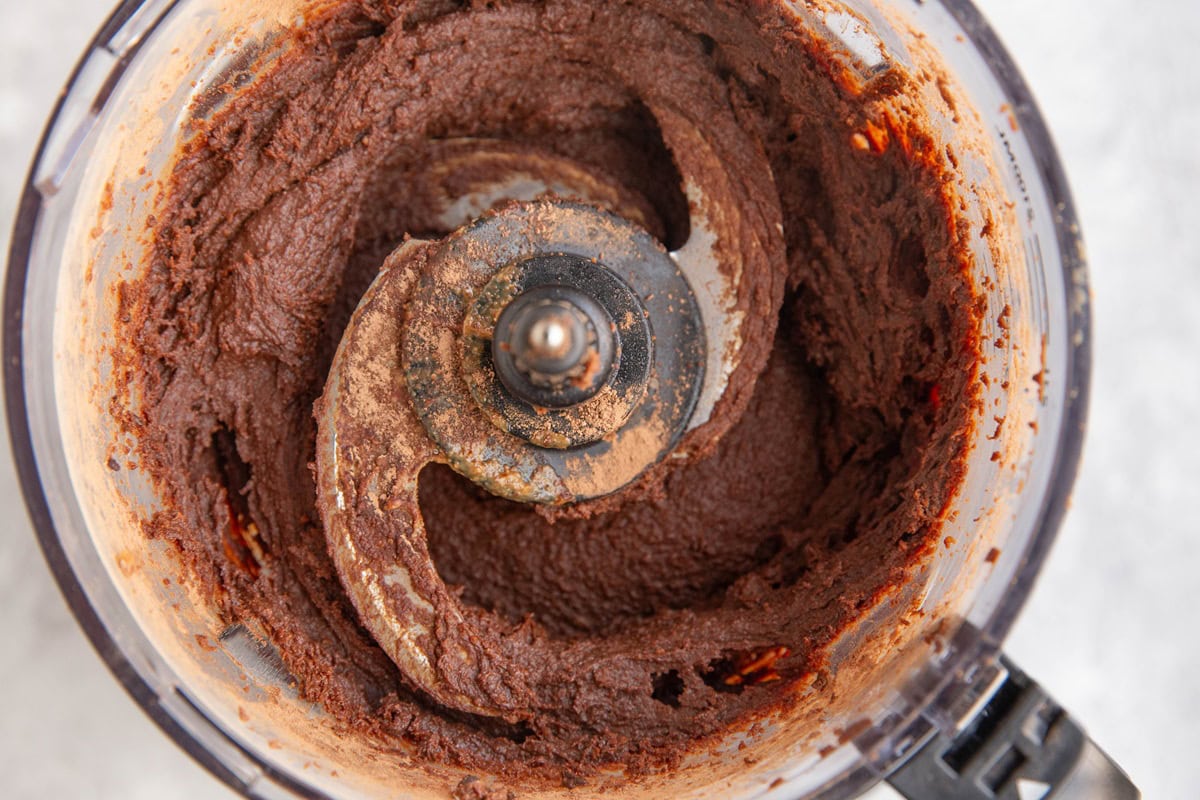 Food processor with blended up chocolate chickpea mixture to make chickpea truffles.