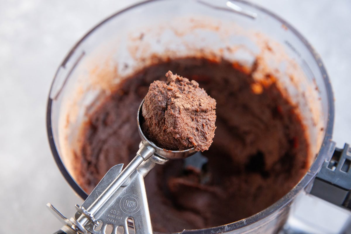 Cookie scoop carrying some chocolate chickpea mixture in order to make truffles.