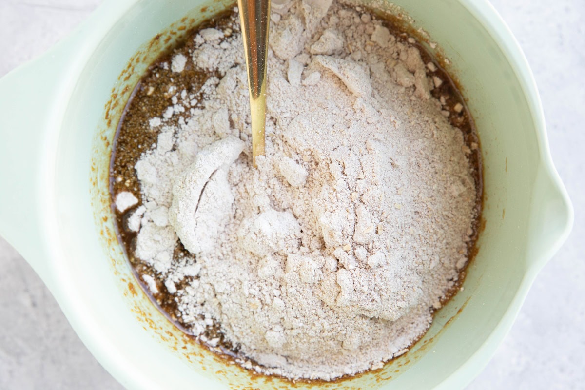 Mixing bowl with molasses mixture on the bottom and oat flour mixture on top, ready to be mixed in.