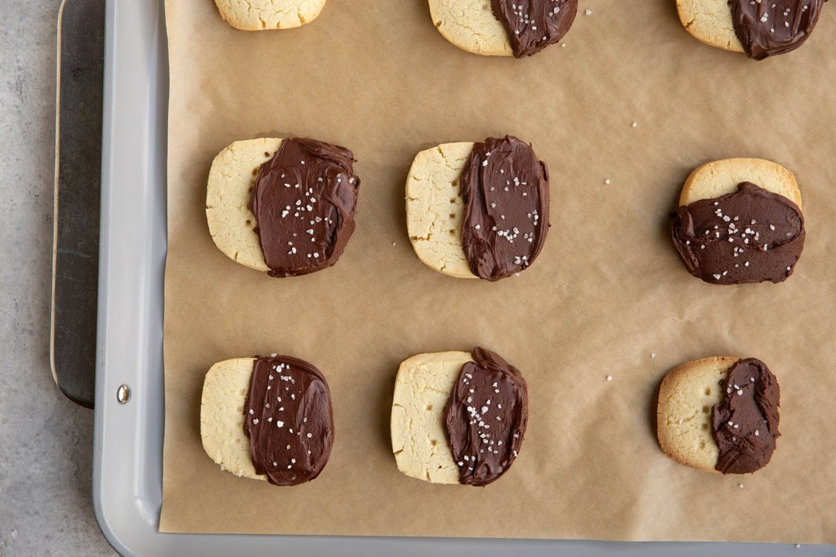 Cookie sheet lined with parchment paper with chocolate-dipped shortbread cookies on top. Ready to serve.