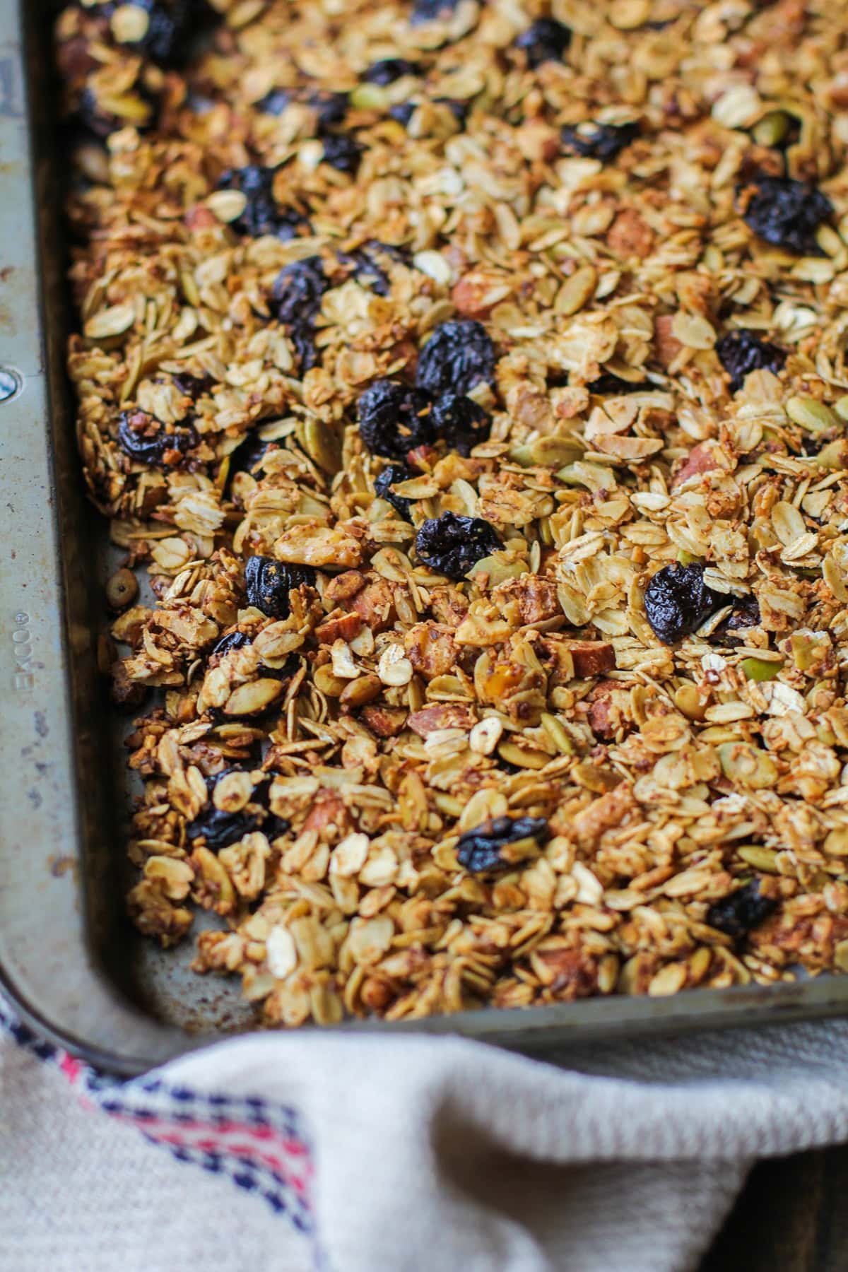 Baking sheet of homemade granola with a burlap napkin next to it.