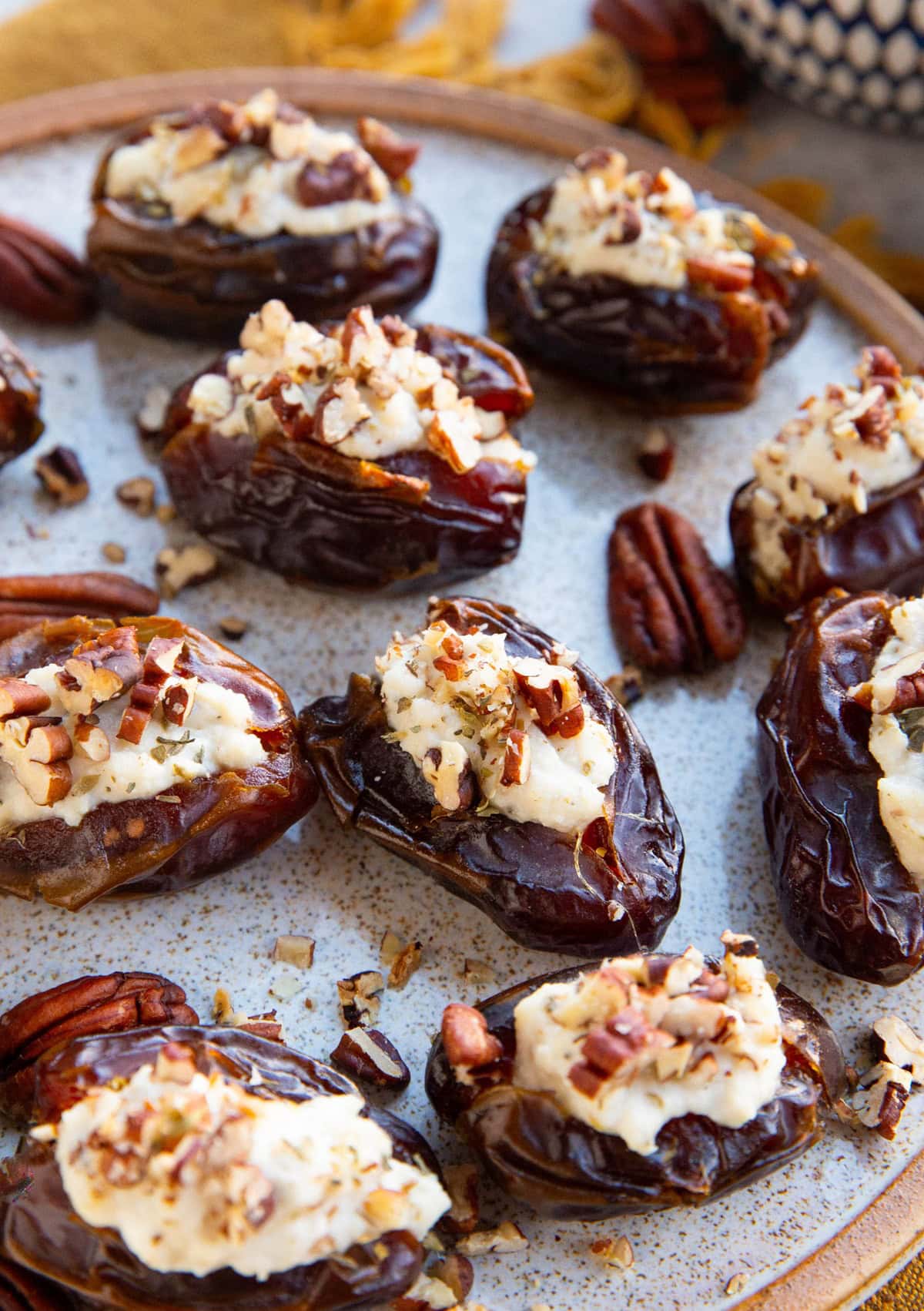 Herbed ricotta stuffed dates on a plate with chopped pecans on top, ready to serve.