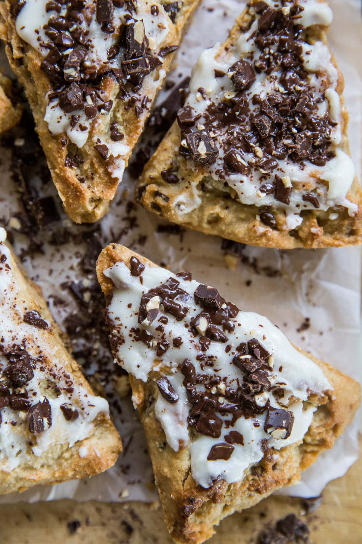 Top down view of four scones that have chopped chocolate bar sprinkled on top. ready to serve.