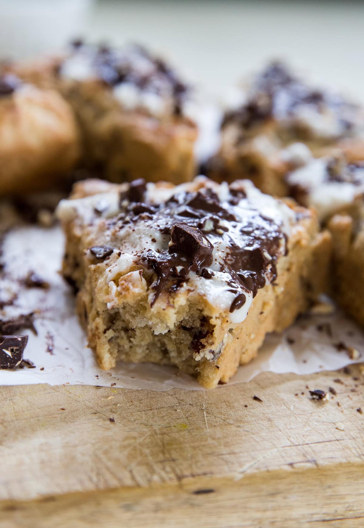 Chocolate chip scone on a wooden cutting board with a bite taken out. More scones in the background.