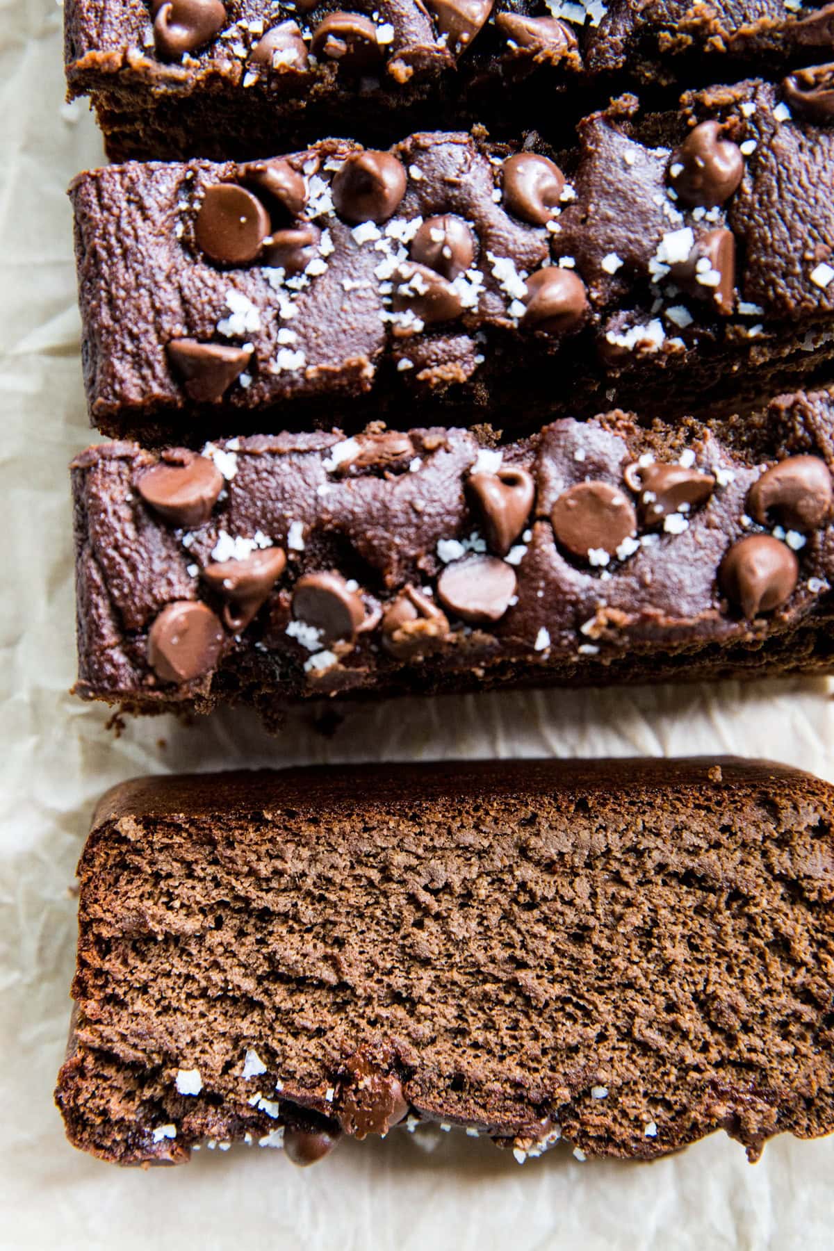 Loaf of chocolate banana bread cut into slices with a close up on a slice so you can see what the inside looks like.