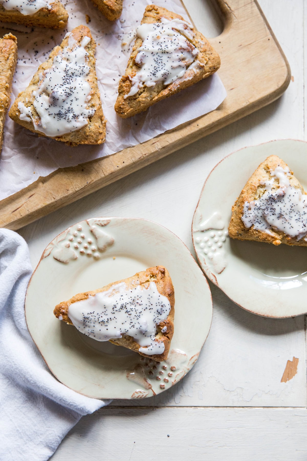 Two plates with lemon poppy seed scones on top and a cutting board with the rest of the scones, ready to serve.