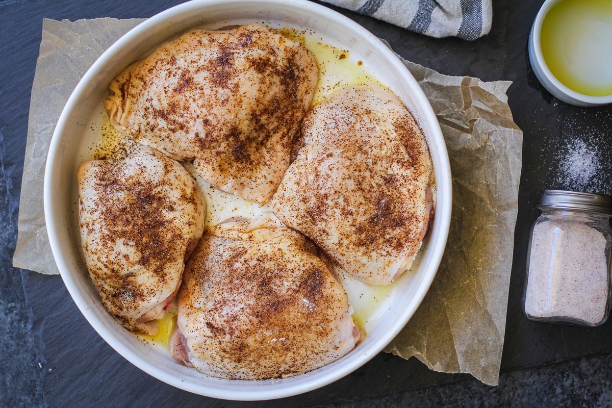 Seasoned chicken thighs in a baking dish, ready to go into the oven.