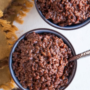 Two bowls of chocolate rice pudding with dark chocolate to the side.