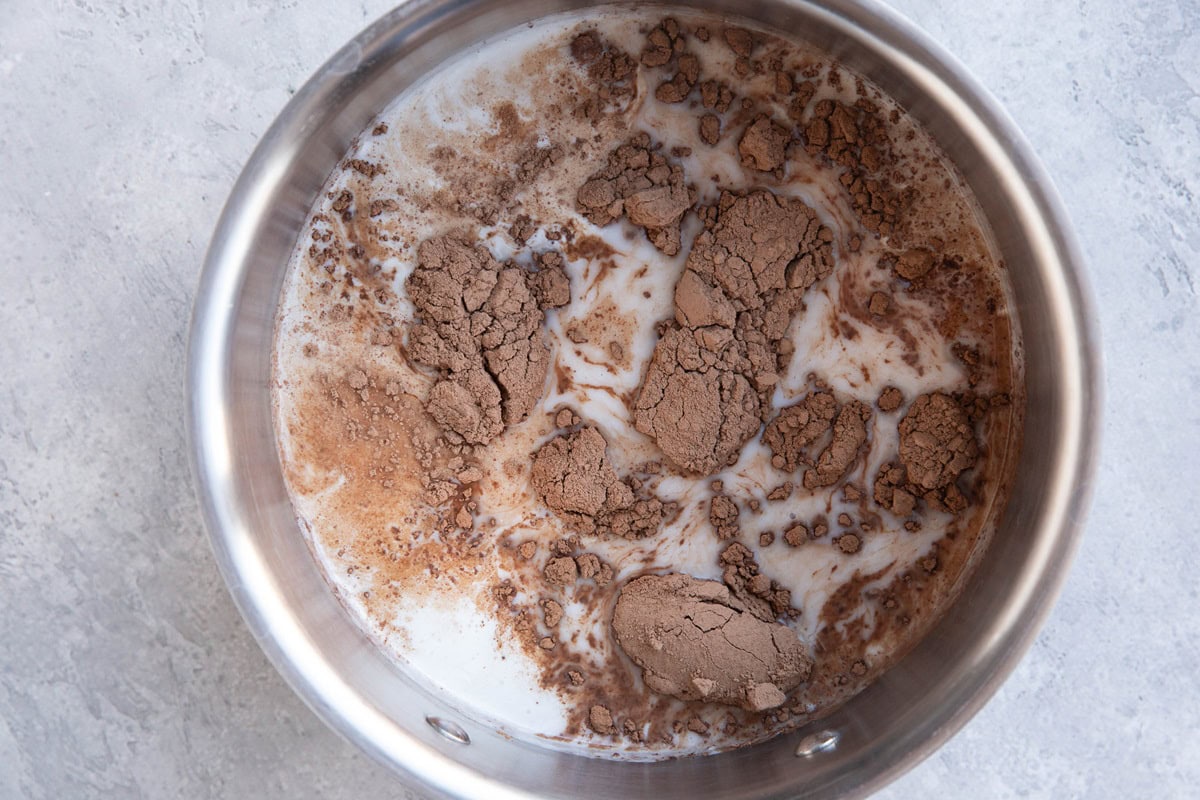 Saucepan with coconut milk and cocoa powder for making chocolate rice pudding.
