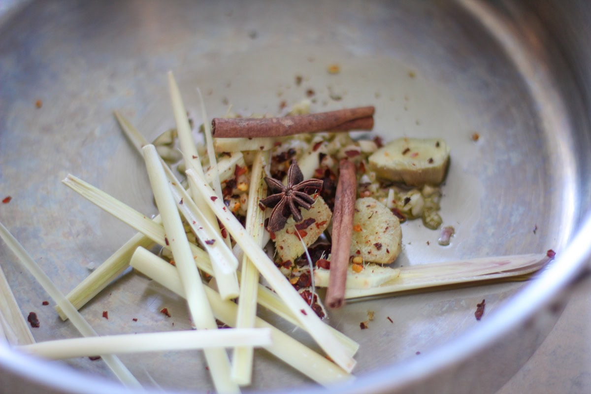 Lemongrass, star anise, red pepper flakes, ginger, and cinnamon sticks in a large pot, being toasted