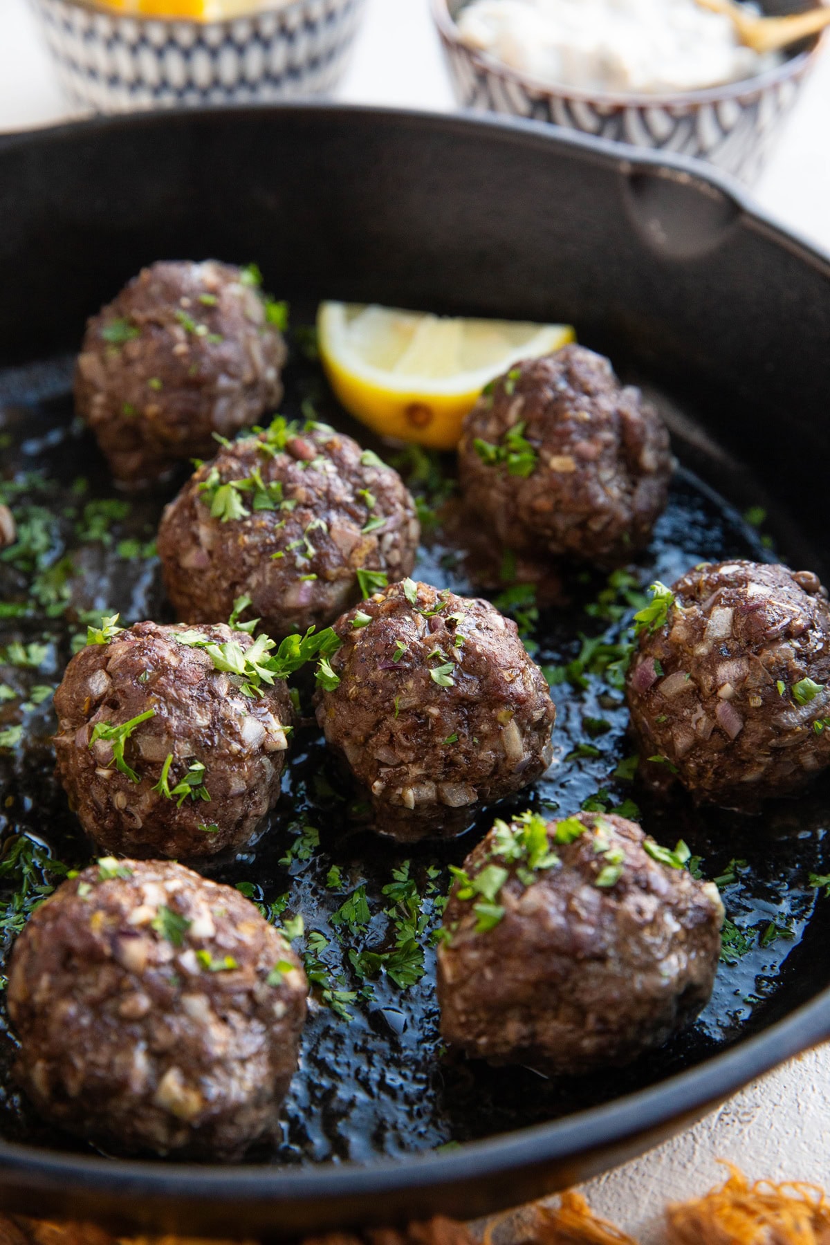 Meatballs in a cast iron skillet, close up, sprinkled with fresh parsley