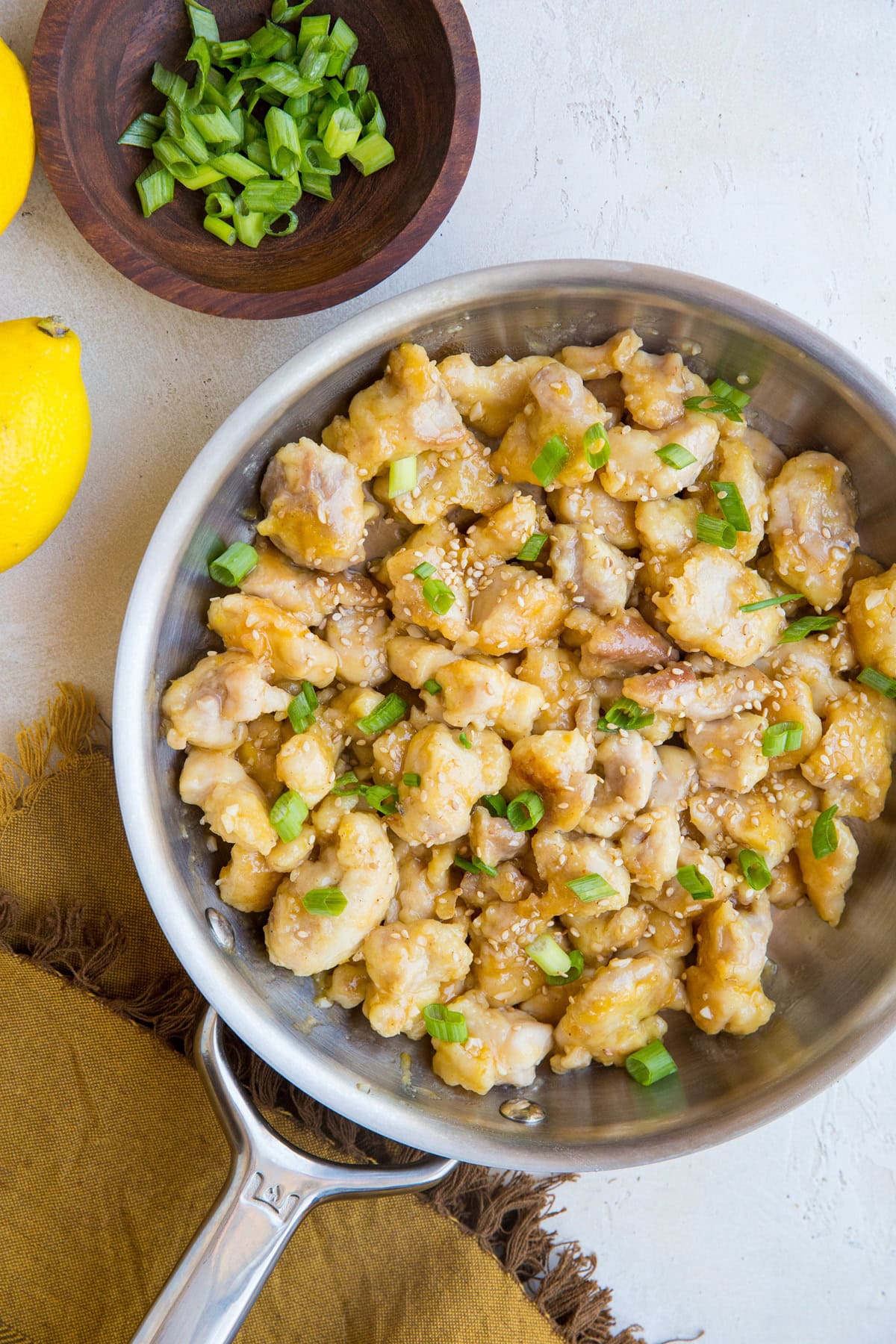 Stainless steel skillet full of lemon chicken with green onions sprinkled on top.