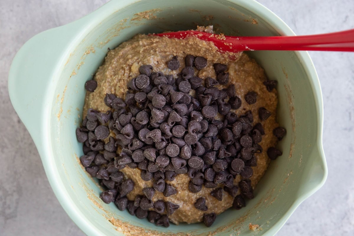 Mixing bowl full of peanut butter banana muffin batter with chocolate chips on top.