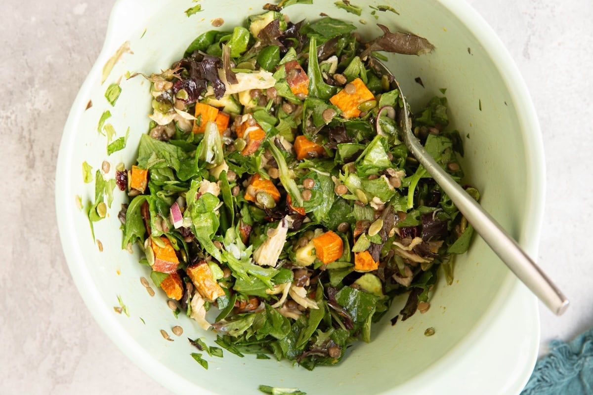Mixing bowl full of salad ingredients mixed together with a spoon, ready to serve.