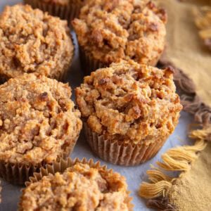 Six sweet potato muffins on a blue-grey surface with a golden napkin to the side, ready to eat.