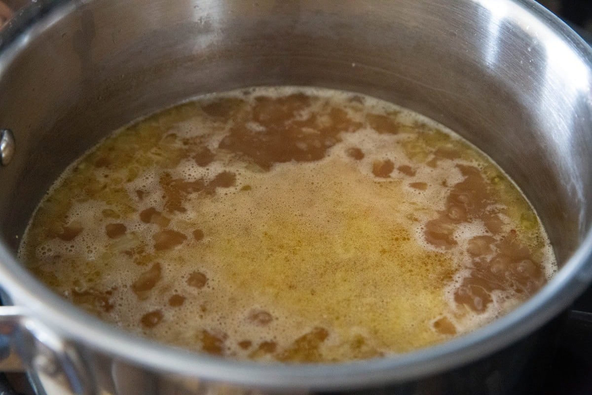 pot with chicken broth and bouillon boiling with rice to make chicken rice.