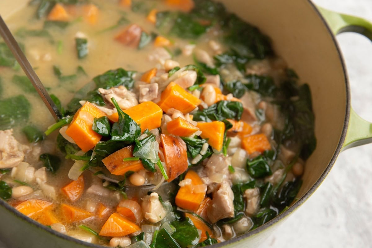 Large pot of creamy chicken and sweet potato soup with spinach and brown rice.