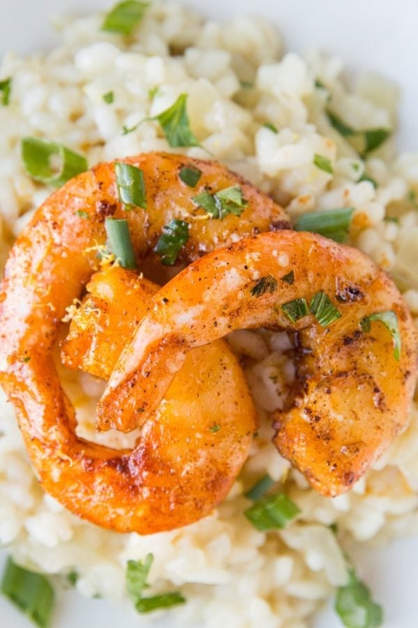 Lemon Garlic shrimp with sear marks on top of risotto sprinkled with green onions.