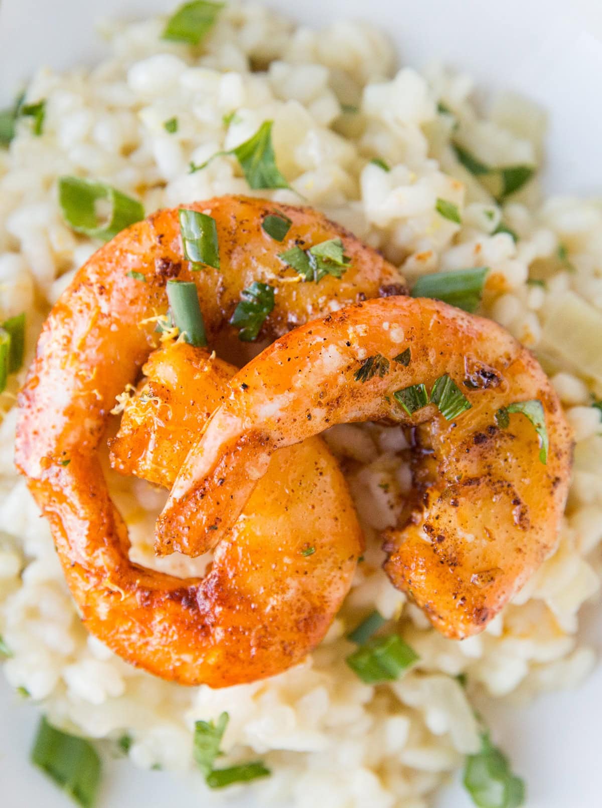 Lemon Garlic shrimp with sear marks on top of risotto sprinkled with green onions.