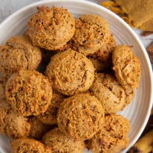 Plate full of peanut butter cookies and a small bowl of peanut butter to the side with a golden napkin. Ready to serve.