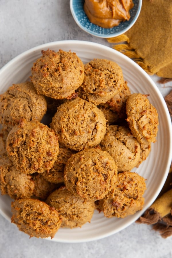 Plate full of peanut butter cookies and a small bowl of peanut butter to the side with a golden napkin. Ready to serve.