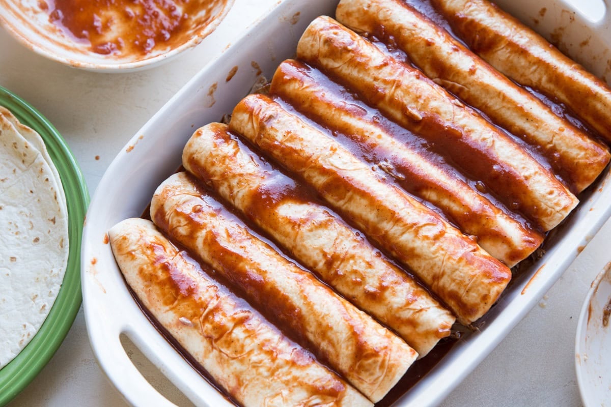Large baking dish filled with 8 pork enchiladas.