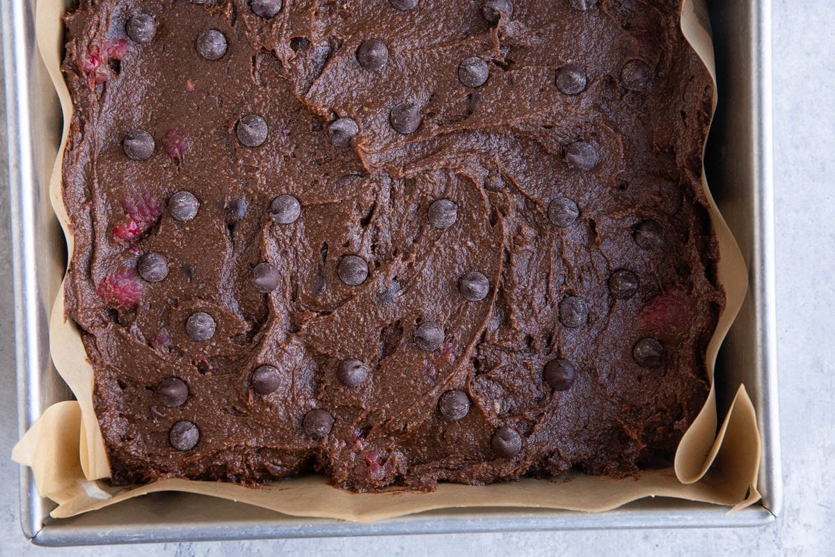 Baking dish with raspberry brownie batter inside, ready to go into the oven.
