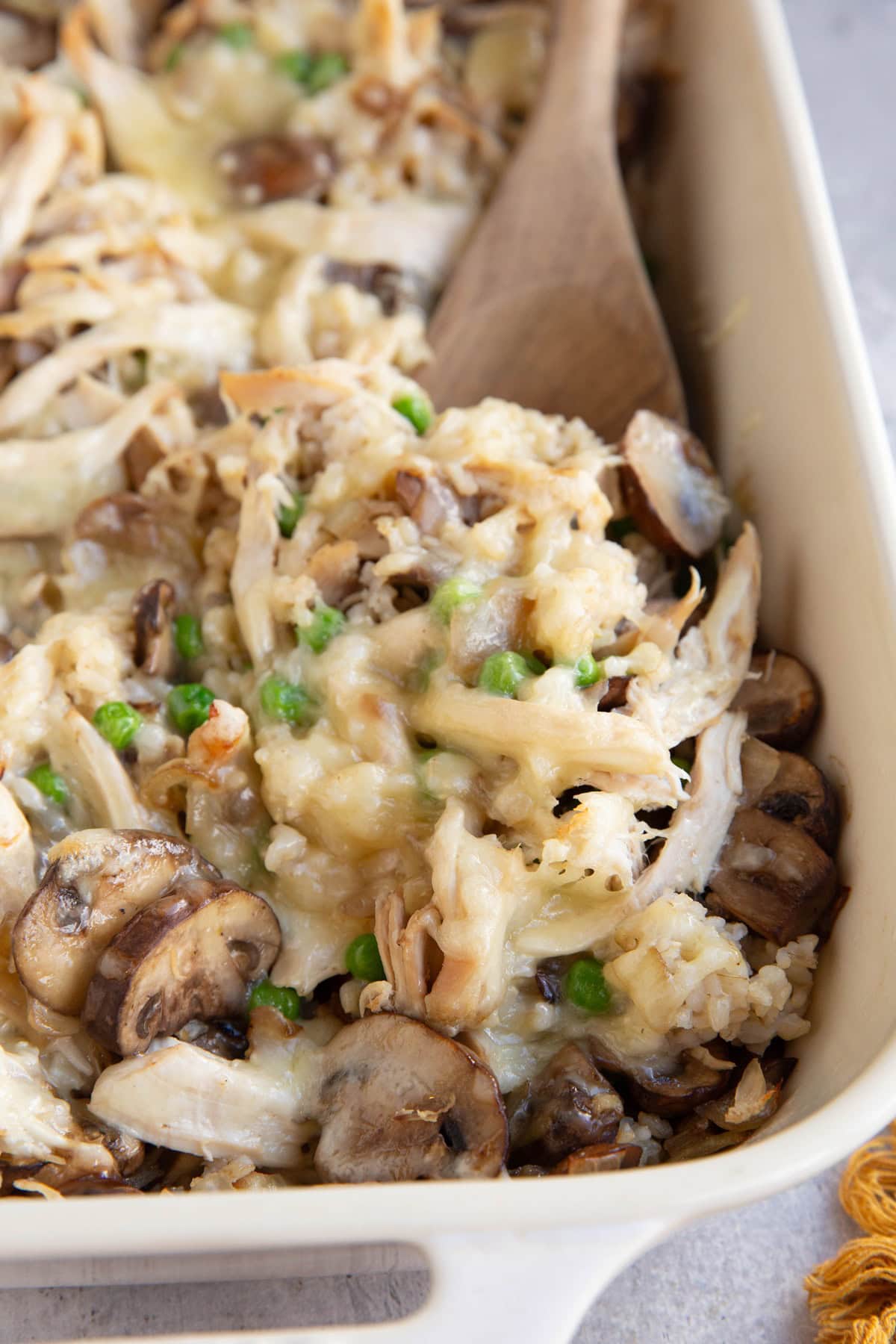 Casserole dish full of shredded chicken casserole with a wooden spoon ready to serve.