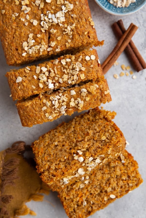 Loaf of sweet potato bread cut into slices with oats sprinkled on top.