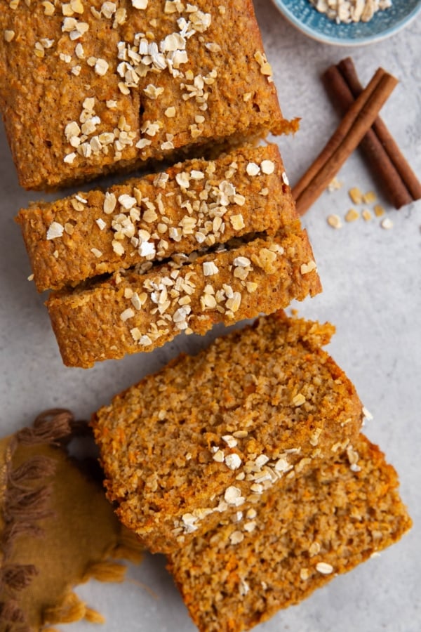 Loaf of sweet potato bread cut into slices with oats sprinkled on top.