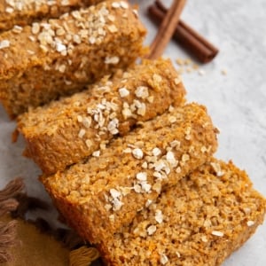 Loaf of sweet potato bread cut into slices with oats sprinkled on top.