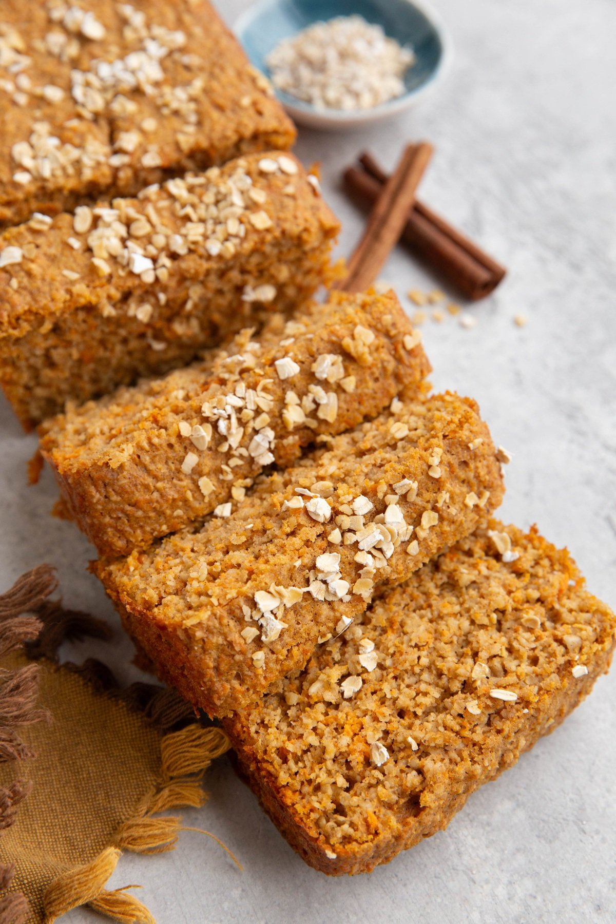 Loaf of sweet potato bread cut into slices with oats sprinkled on top.