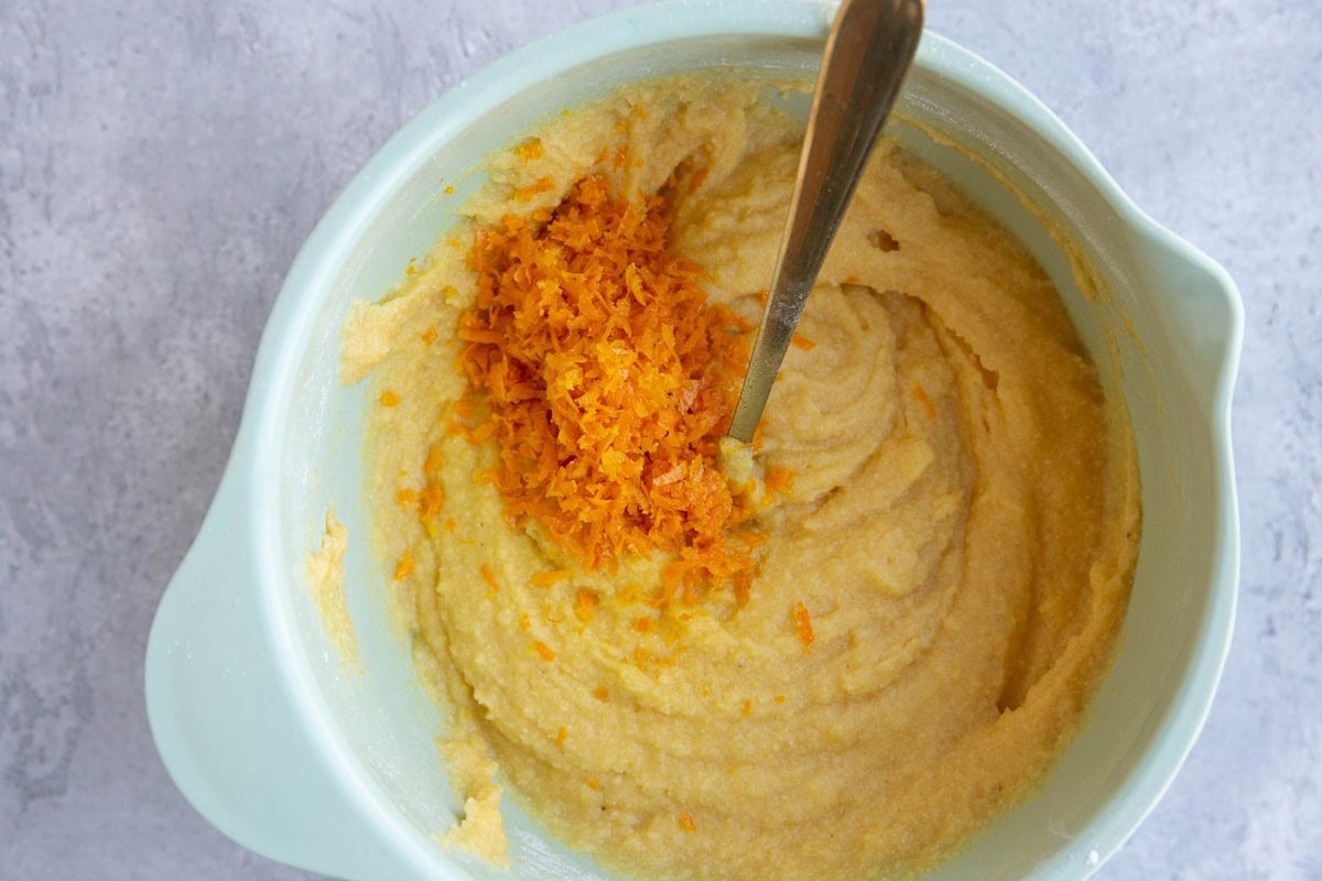 Pound cake batter in a mixing bowl with orange zest on top.