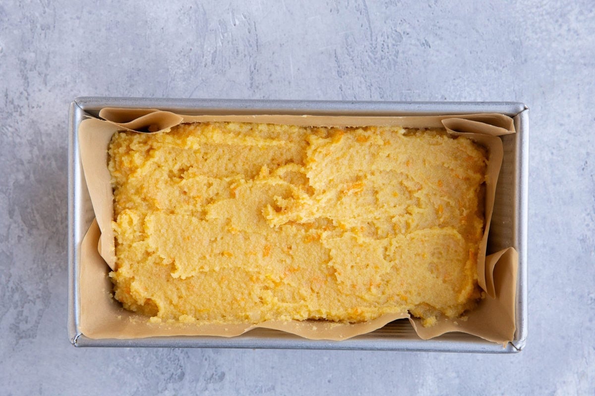 Orange pound cake batter in a parchment-lined baking pan.